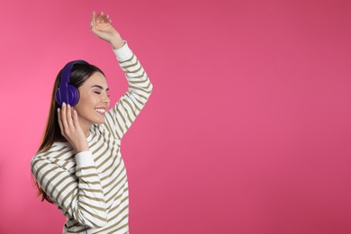 Photo of Attractive young woman enjoying music in headphones on color background. Space for text