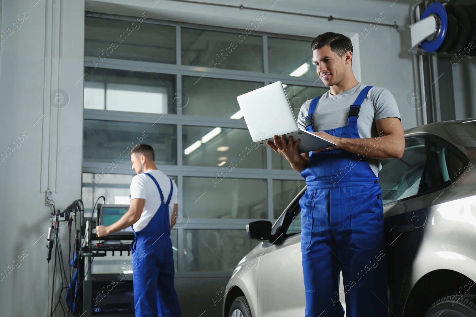 Photo of Mechanic with laptop doing car diagnostic at automobile repair shop