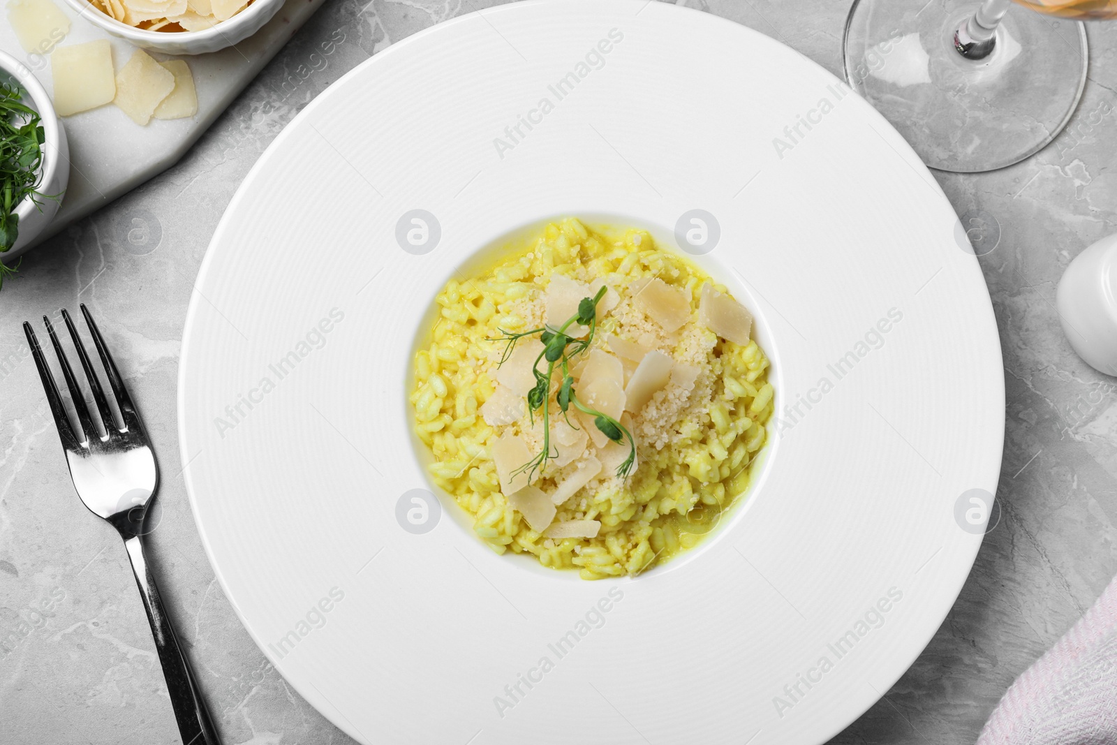 Photo of Delicious risotto with cheese on grey marble table, flat lay