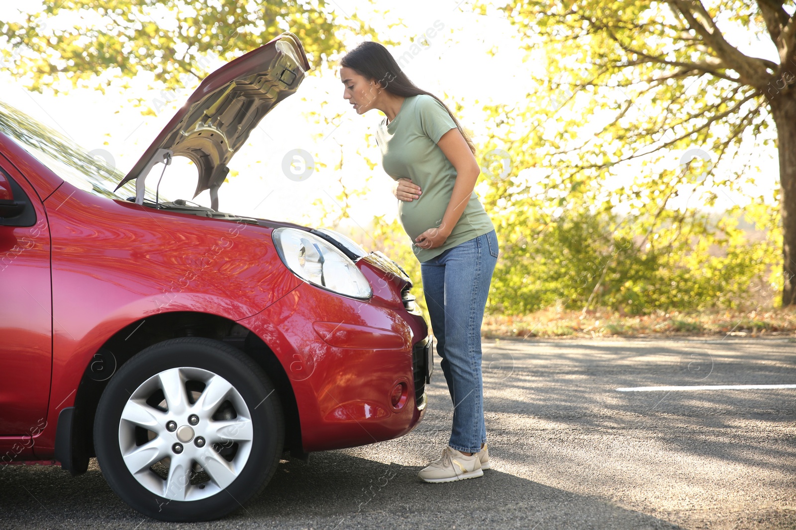 Photo of Stressed pregnant woman near broken car outdoors