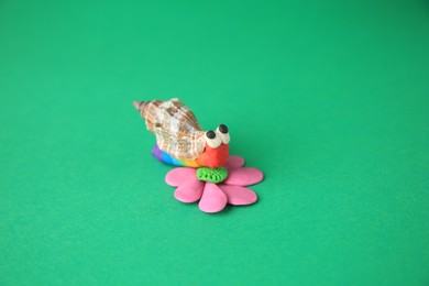 Photo of Beautiful plasticine snail on green background. Children's handmade ideas