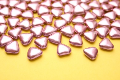 Many delicious heart shaped candies on yellow background