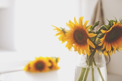 Photo of Vase with beautiful yellow sunflowers on table, space for text