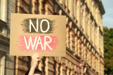 Photo of Woman holding poster with words No War outdoors. Space for text