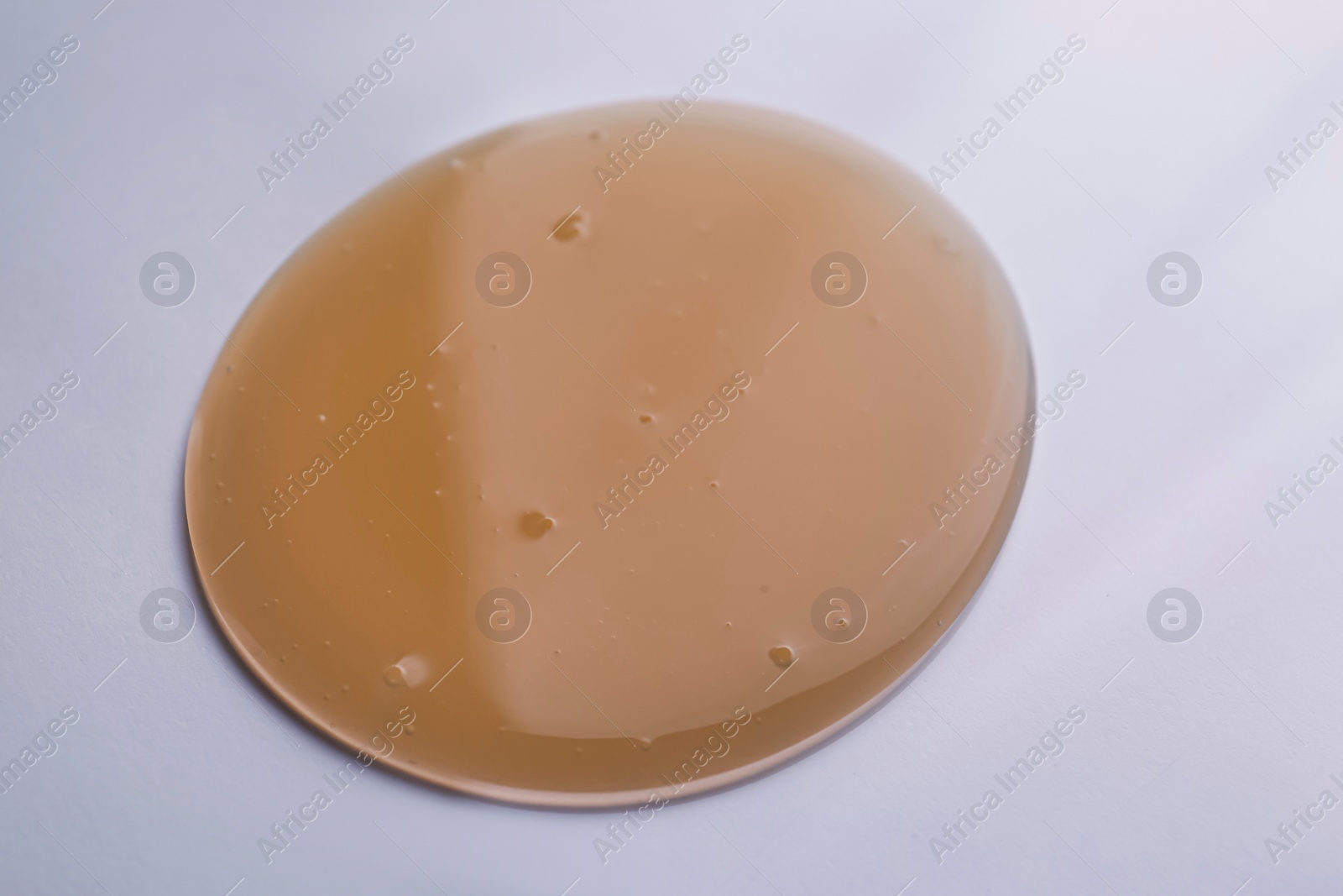 Photo of Sample of brown shower gel on white background