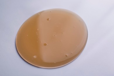 Photo of Sample of brown shower gel on white background