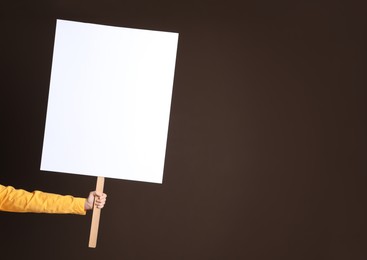Photo of Woman holding blank sign on brown background, closeup. Space for design