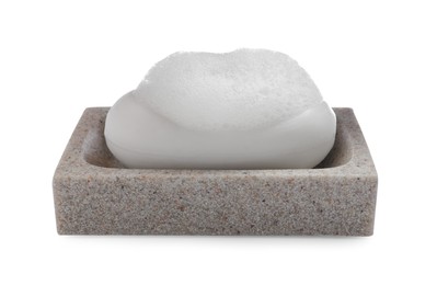 Soap bar with fluffy foam in holder on white background