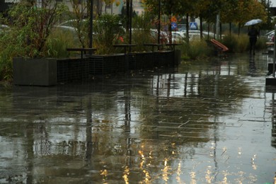 Wet outdoor cafe furniture and puddles on pavement after rain