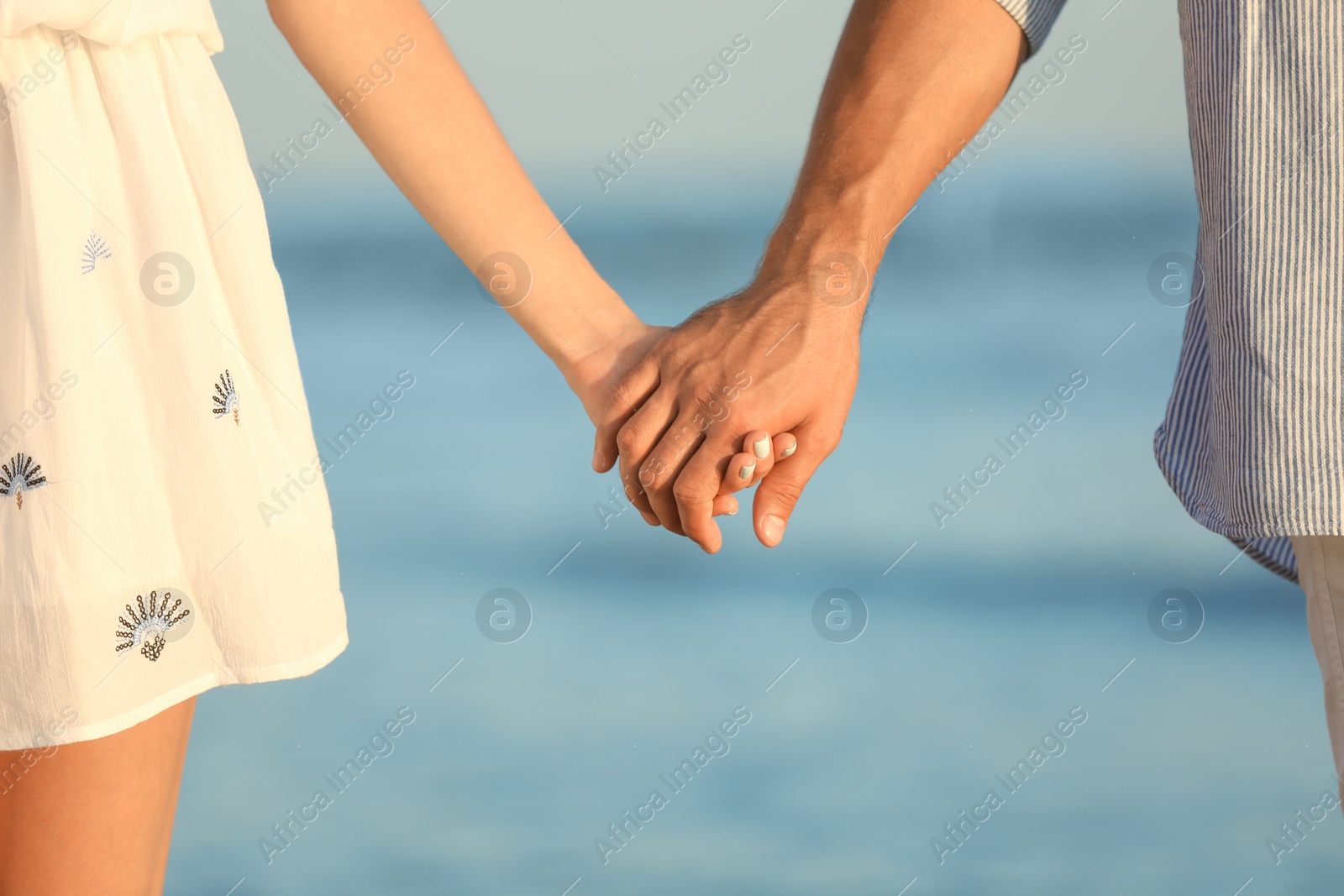 Photo of Happy young couple holding hands at beach on sunny day, closeup