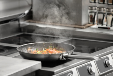 Photo of Cooking tasty food on stove in restaurant kitchen