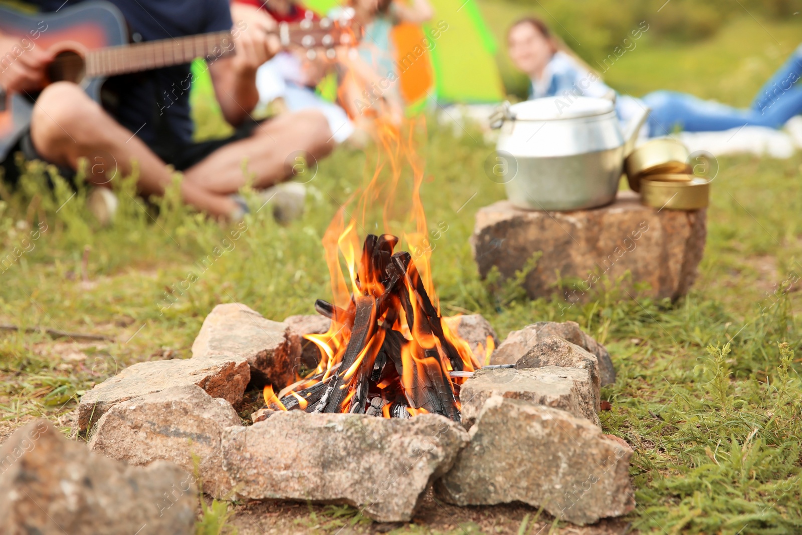 Photo of Group of people resting outdoors, focus on bonfire. Camping season