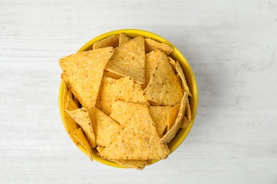 Bowl with tasty Mexican nachos chips on white wooden table, top view