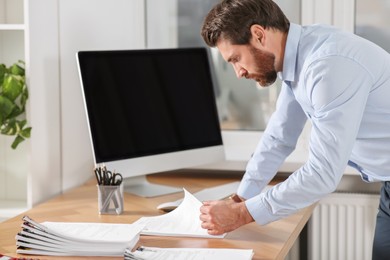 Photo of Businessman working with documents at wooden table in office