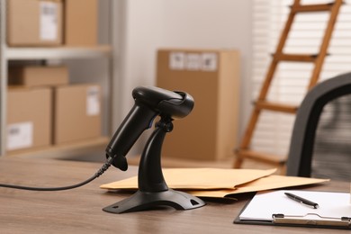 Photo of Black modern barcode scanner on wooden table in office. Online store