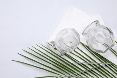 Cupping set and green leaf on white table, flat lay. Space for text