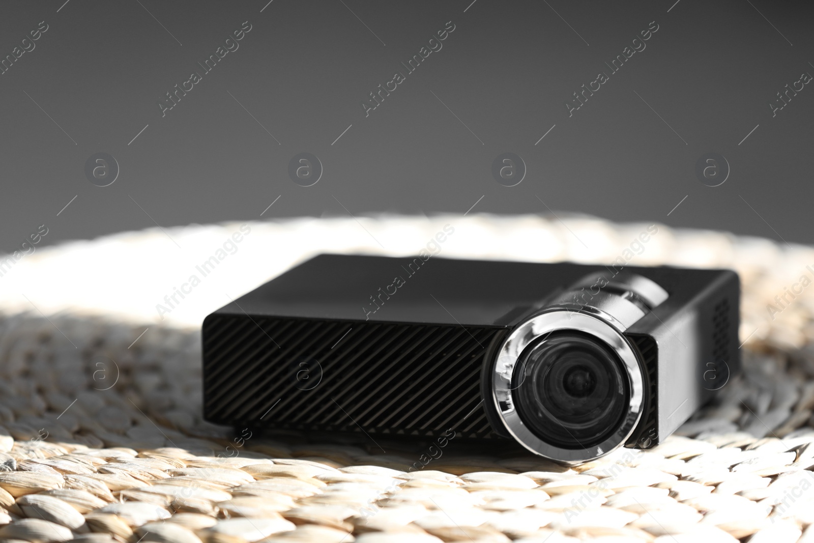 Photo of Modern video projector on wicker pouf indoors
