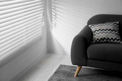 Photo of Window with closed horizontal blinds and armchair in room