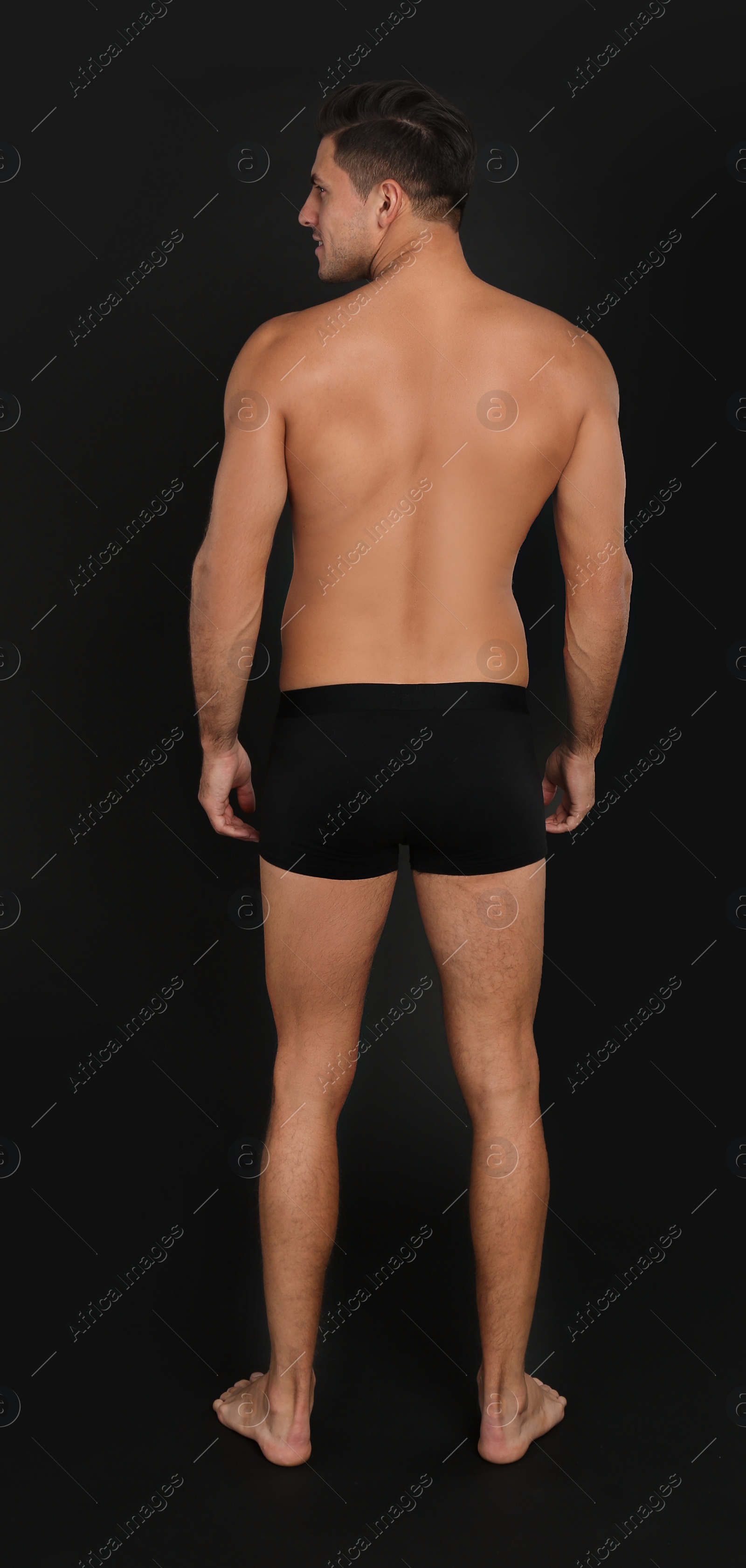 Photo of Man in underwear on black background, back view