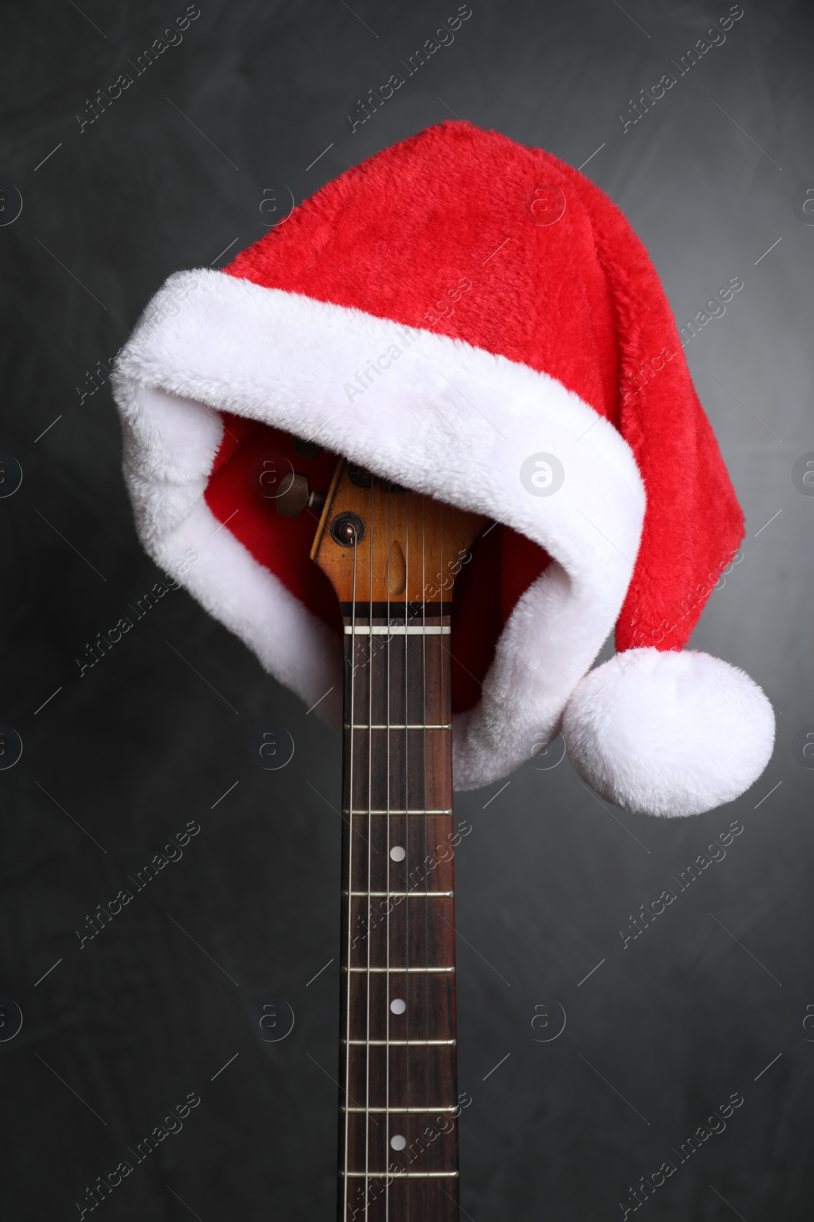 Photo of Guitar with Santa hat on black background. Christmas music