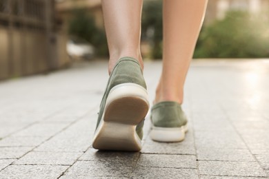 Photo of Woman in stylish loafers walking on city street, closeup