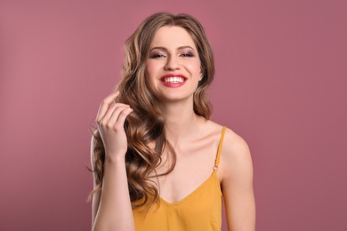 Portrait of young woman with long beautiful hair on color background