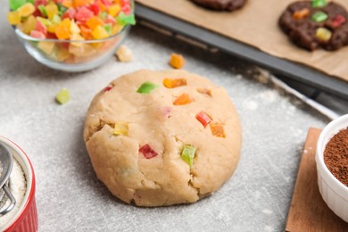 Photo of Unbaked cookie with candied fruits on grey table, closeup