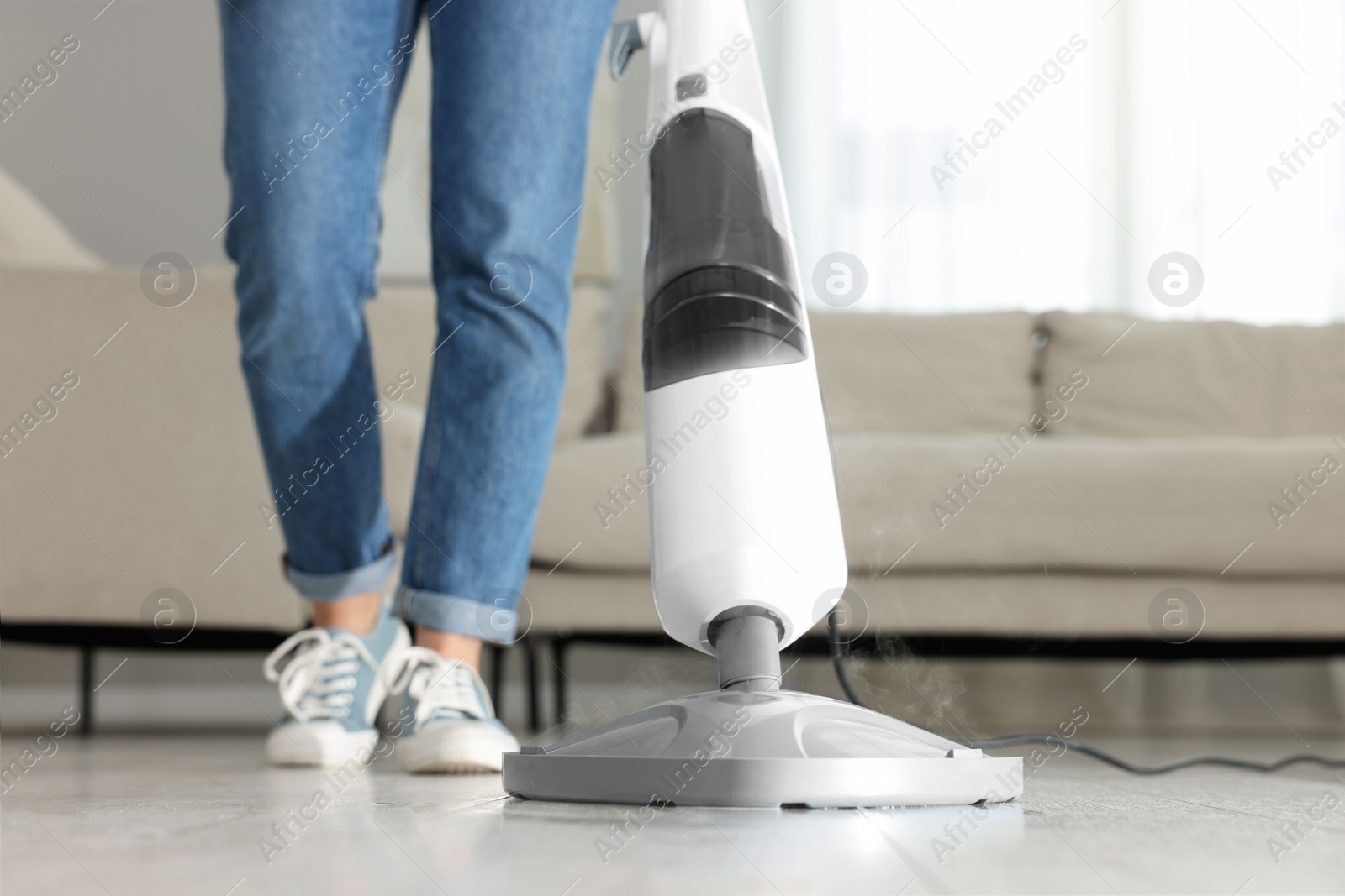 Photo of Woman cleaning floor with steam mop at home, closeup