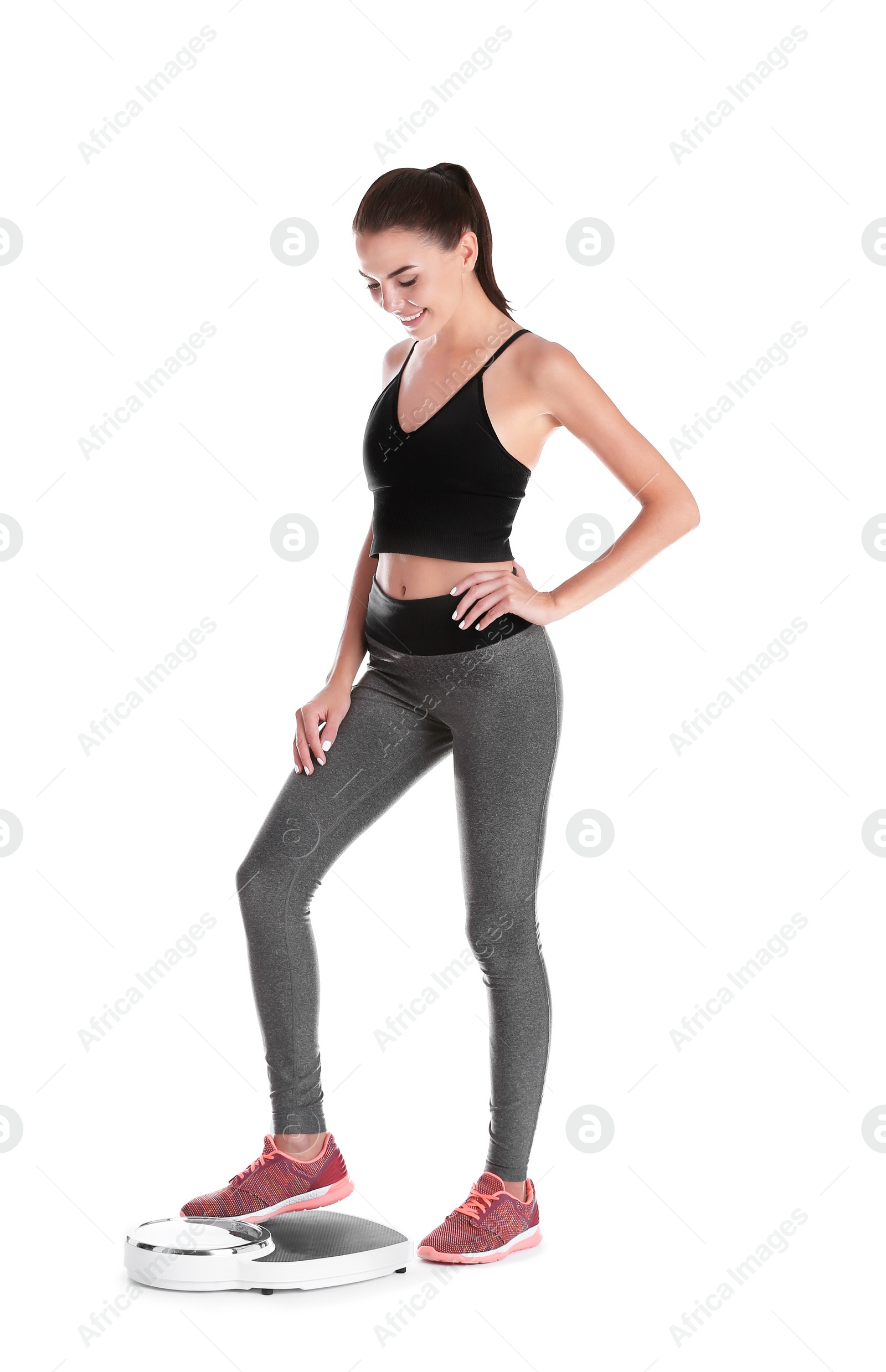 Photo of Happy young woman measuring her weight using scales on white background. Weight loss motivation