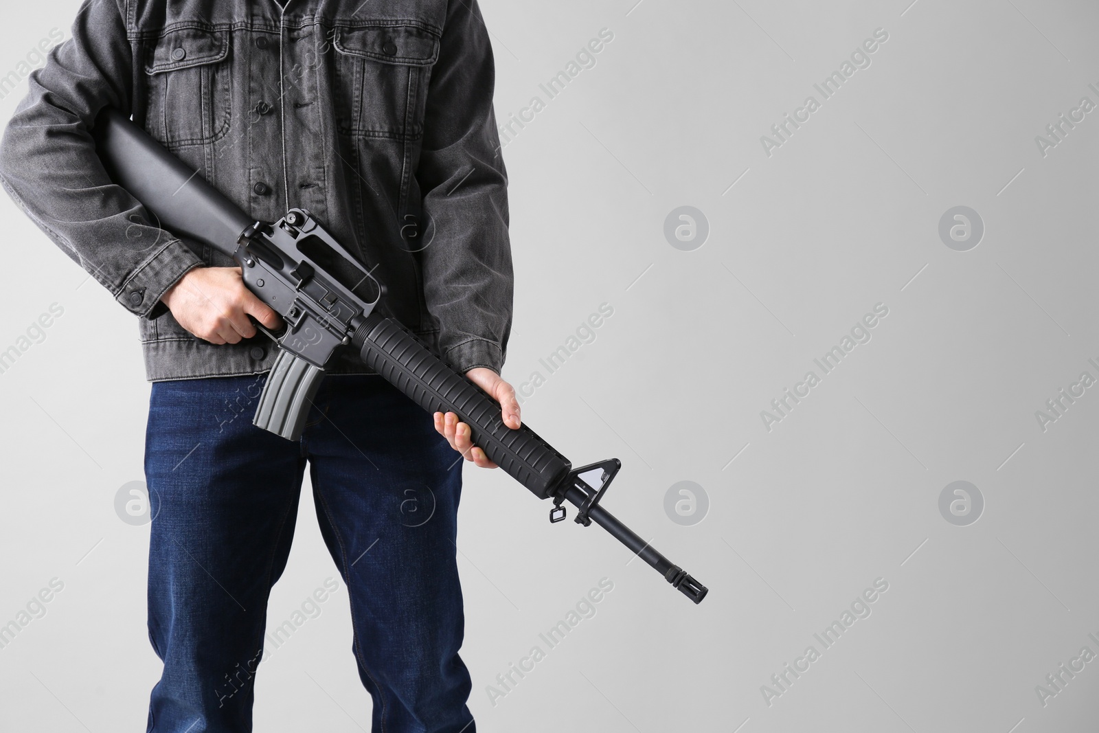 Photo of Assault gun. Man holding rifle on light background, closeup. space for text