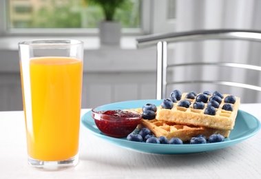 Photo of Delicious waffles with blueberries and juice on white table