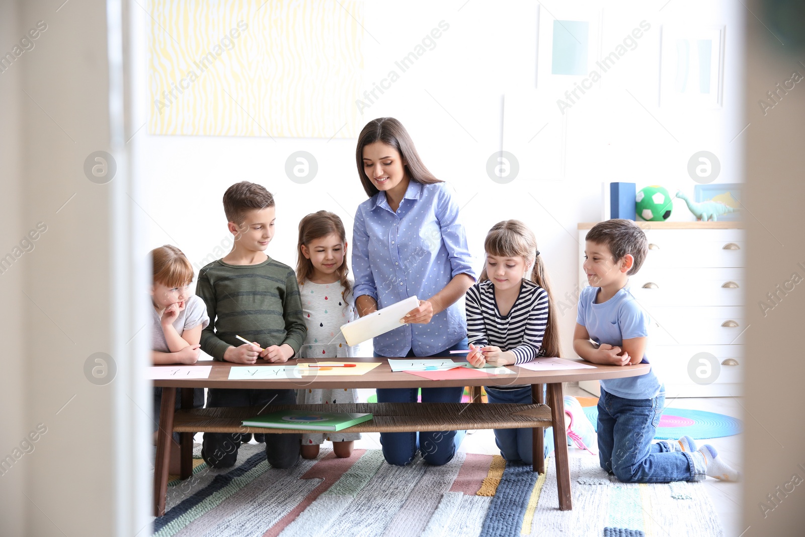 Photo of Cute little children with teacher in classroom at school