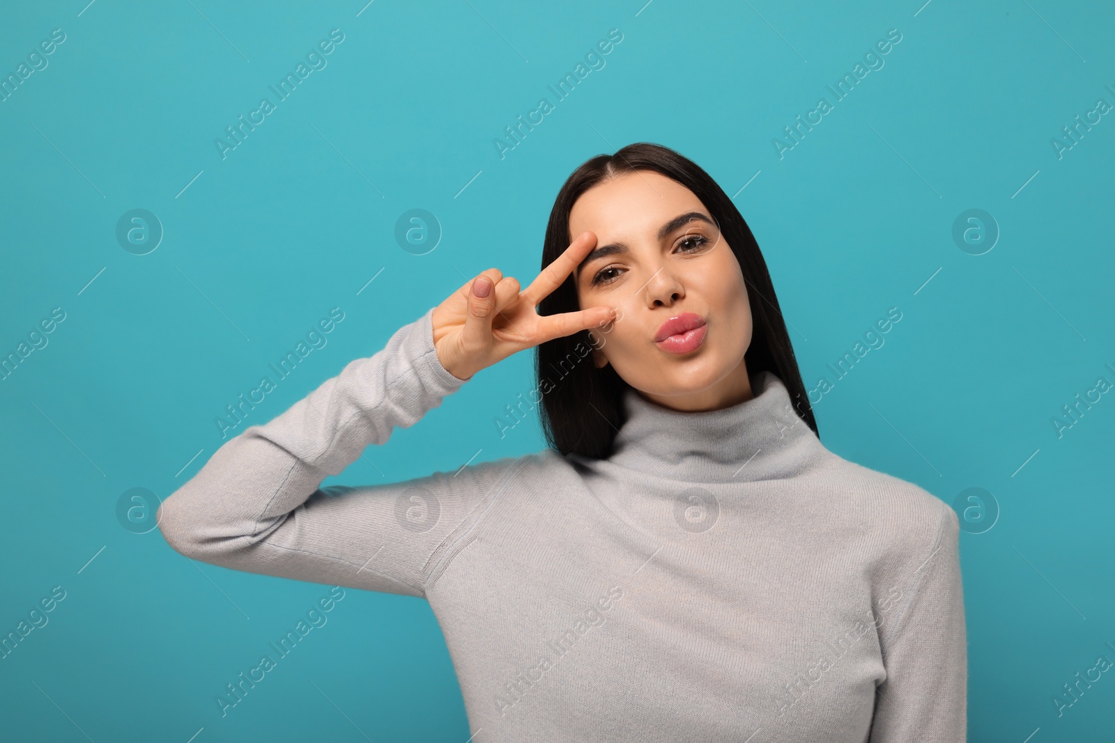 Photo of Beautiful young woman blowing kiss on light blue background