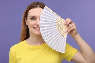 Photo of Happy woman with yellow hand fan on violet background