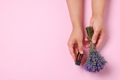 Woman with bottle of lavender essential oil and flowers on pink background, top view. Space for text