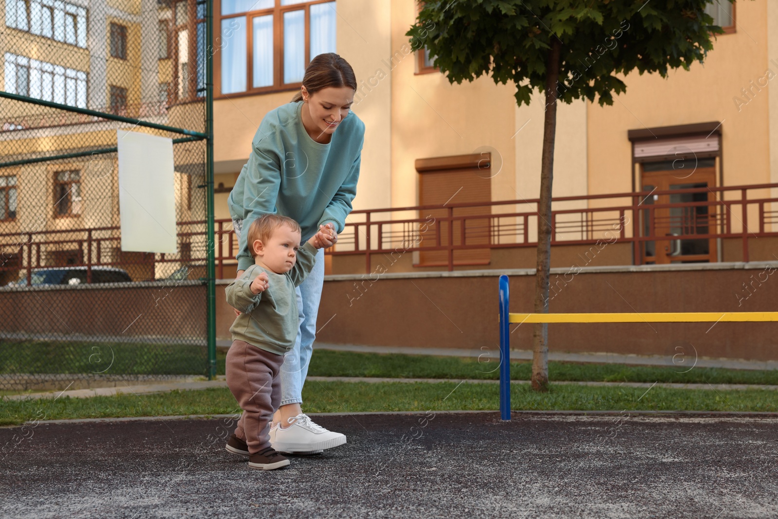 Photo of Happy nanny walking with cute little boy outdoors, space for text