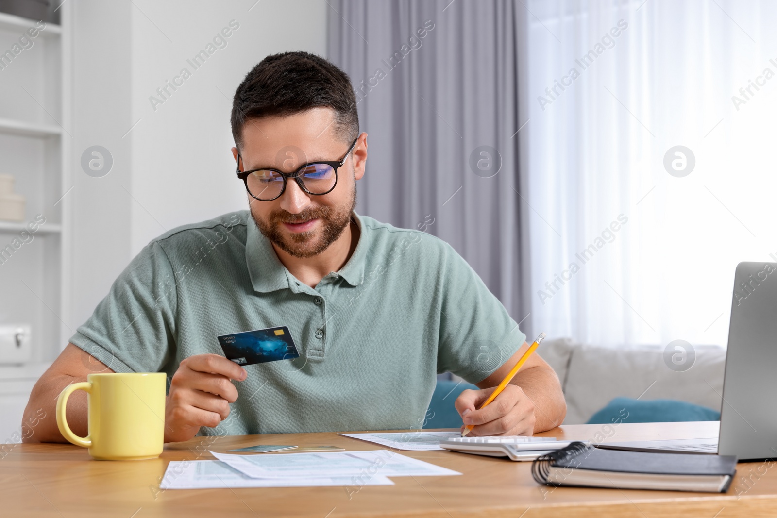 Photo of Man with credit card using laptop for paying taxes online at home