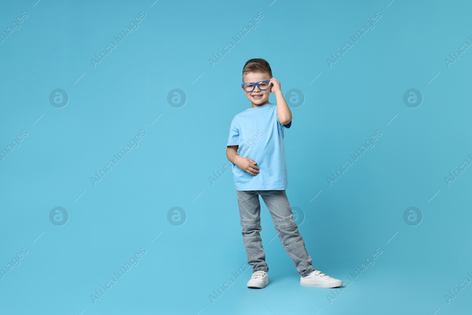 Photo of Happy little boy dancing on light blue background. Space for text