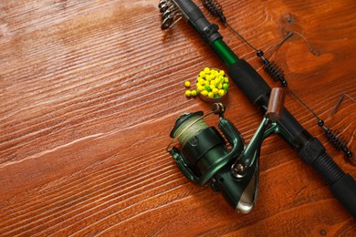 Photo of Fishing rod with reel and bait on wooden table, above view. Space for text