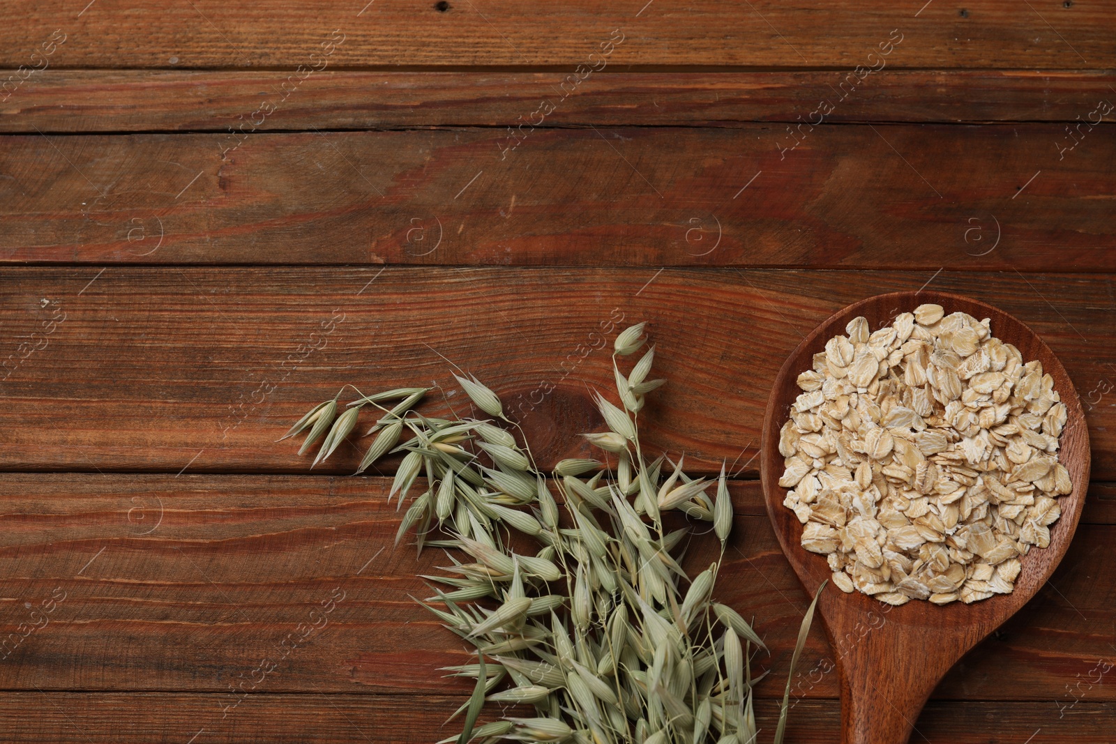 Photo of Spoon with oatmeal and floret branches on wooden table, flat lay. Space for text