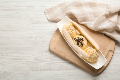 Photo of Delicious banana split ice cream with toppings on white wooden table, top view. Space for text