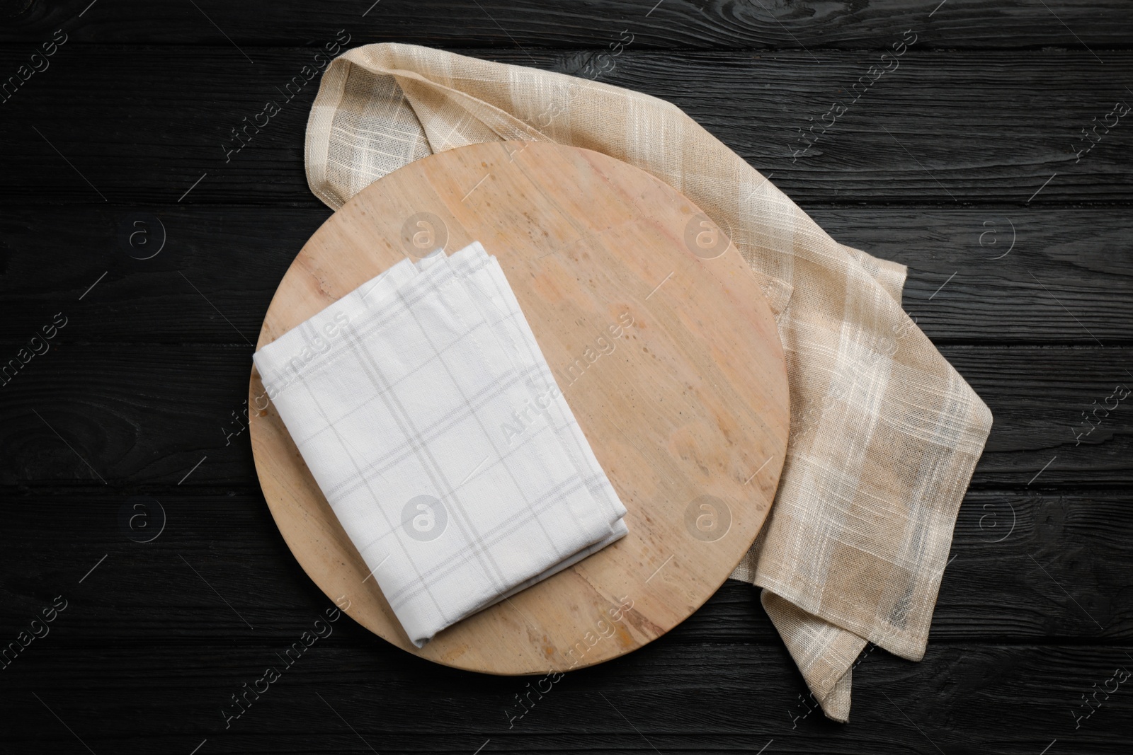 Photo of Kitchen towels and cutting board on black wooden table, top view