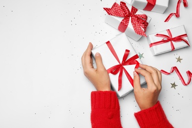 Photo of Young woman holding Christmas gift on white background, flat lay. Space for text