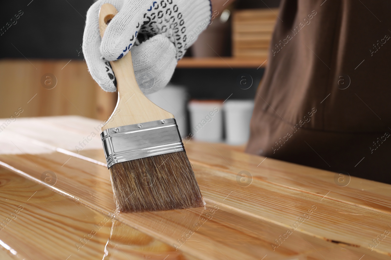 Photo of Man varnishing wooden surface with brush indoors, closeup