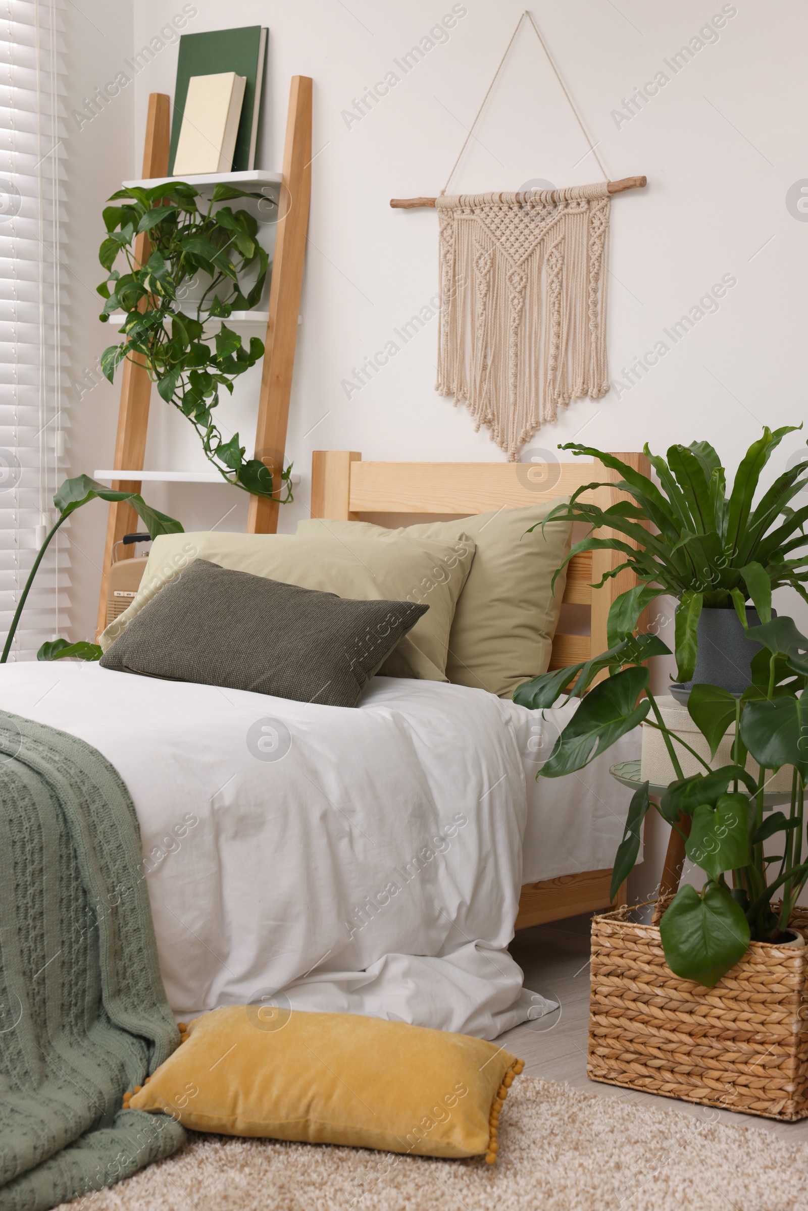 Photo of Large comfortable bed and potted houseplants in stylish bedroom. Interior design