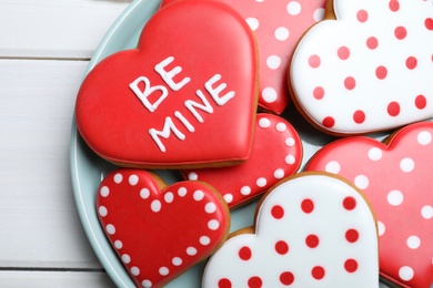 Photo of Decorated heart shaped cookies on white wooden table, top view. Valentine's day treat