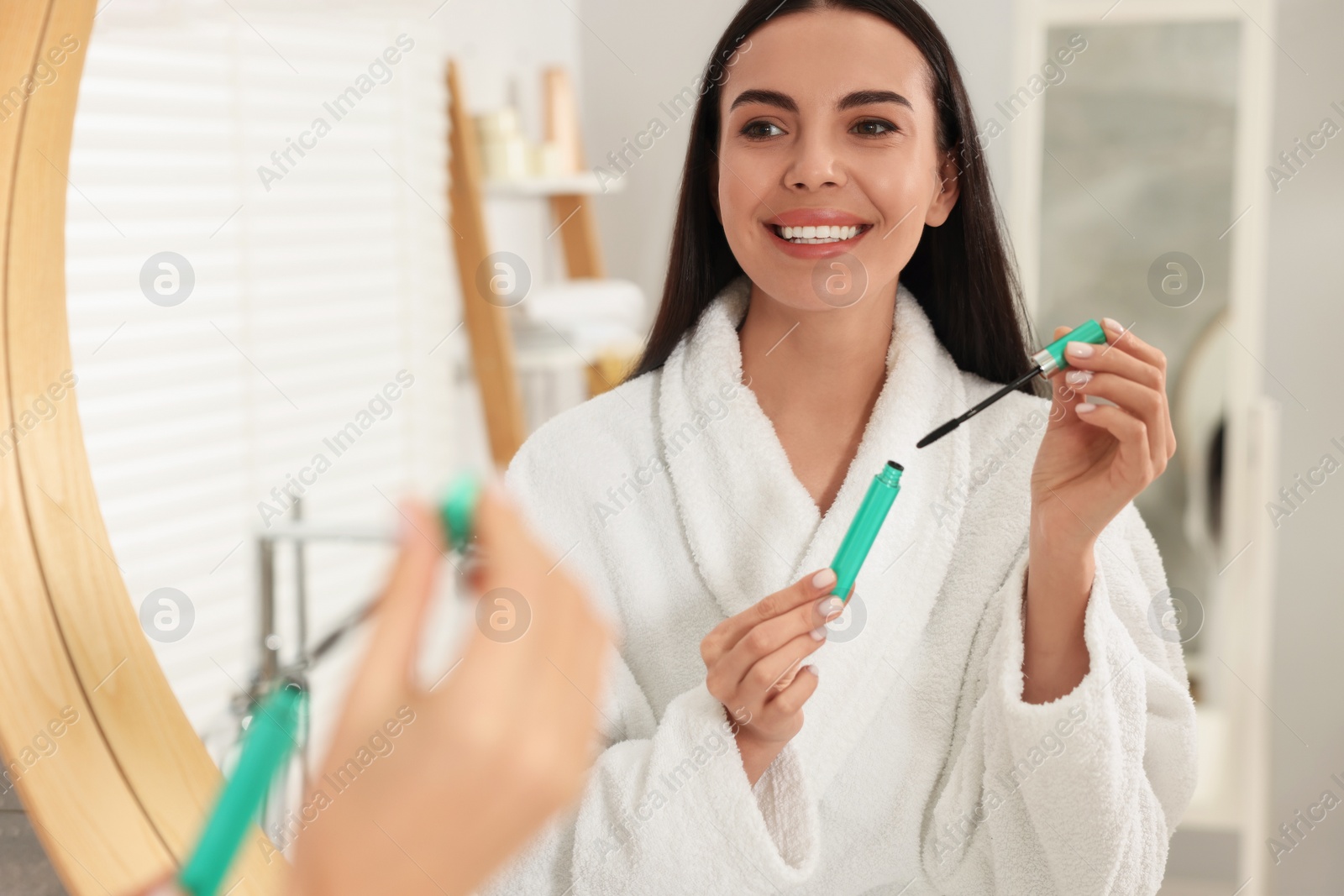 Photo of Beautiful young woman with mascara in bathroom