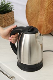 Photo of Woman with electric kettle in kitchen, closeup