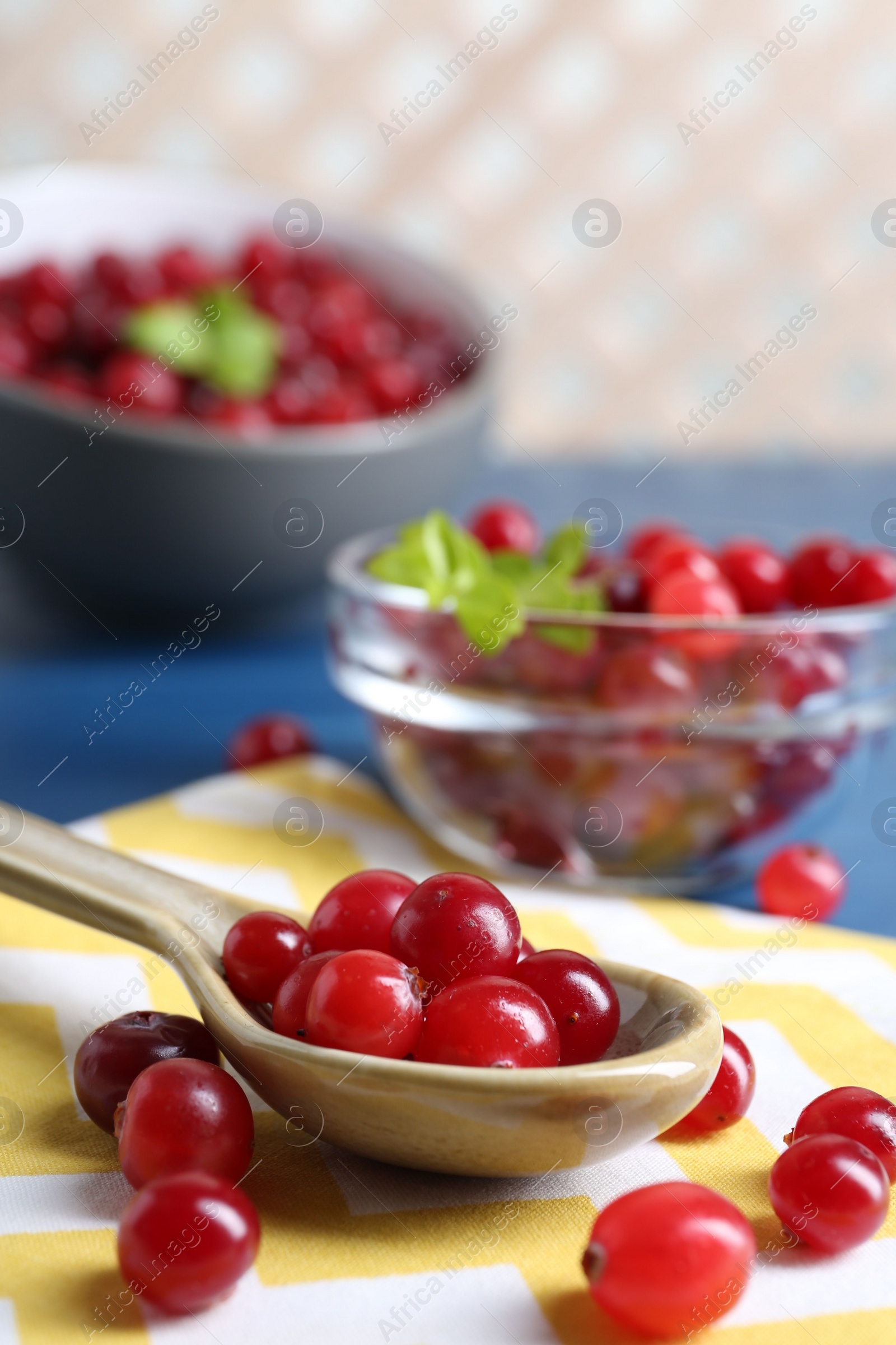 Photo of Spoon with fresh ripe cranberries on table, closeup