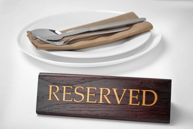 Photo of Elegant table setting and RESERVED sign in restaurant